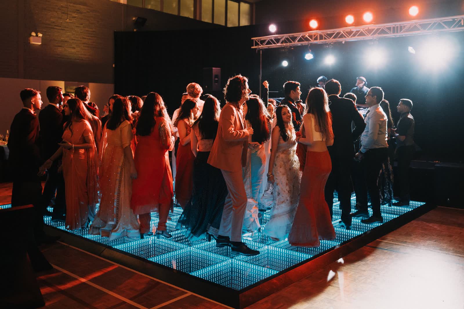 Crowd dancing on the 3D infinity LED dance floor under truss lighting at a Perth event